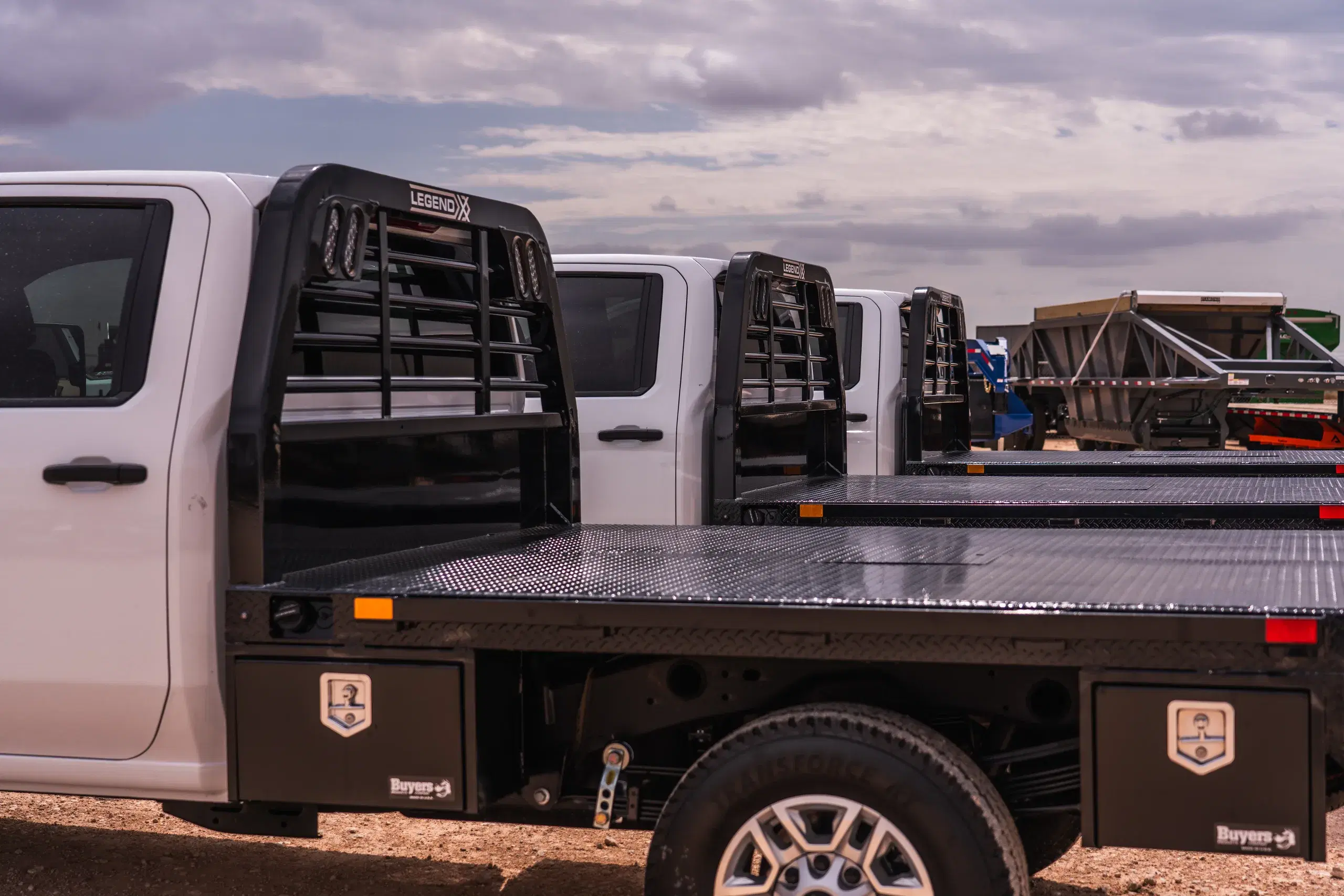 Row of white commercial trucks equipped with black Legend X flatbeds
