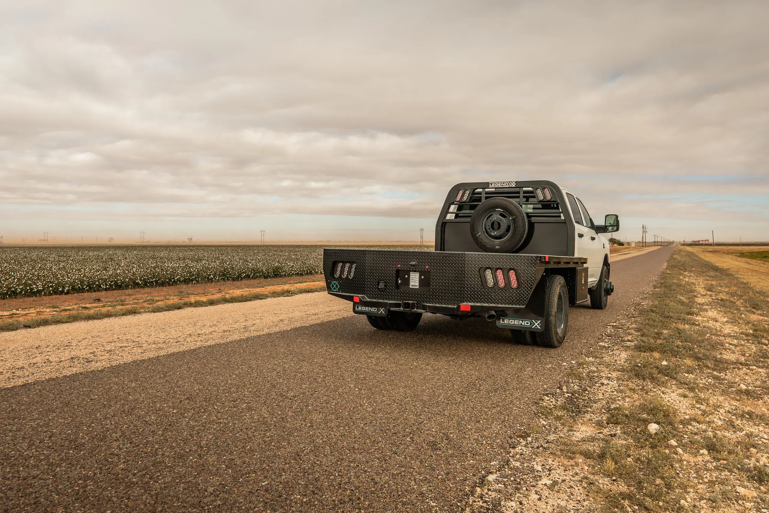 White Ram dually with a Spartan flatbed on a farm road under a big sky
