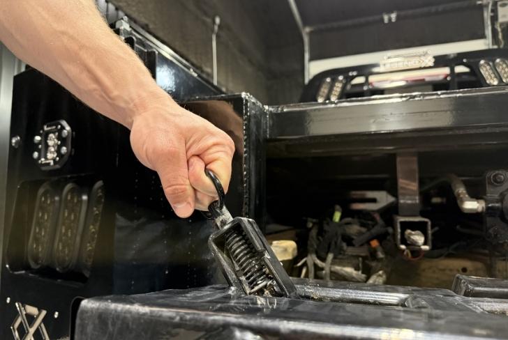 Hand operating the easy latch that secures the Spike attachment at the rear of a Legend X bed
